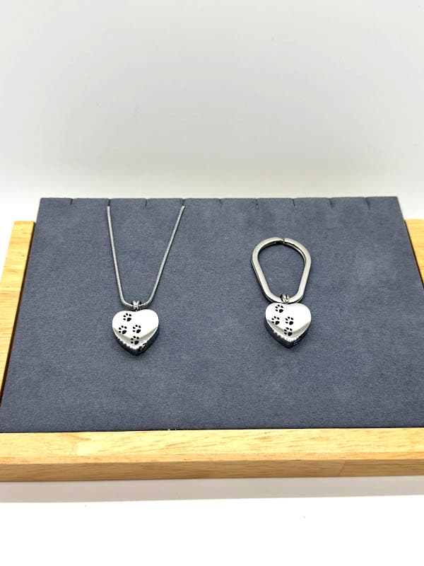 Silver heart with black paw prints. Wearable as necklace or keychain.