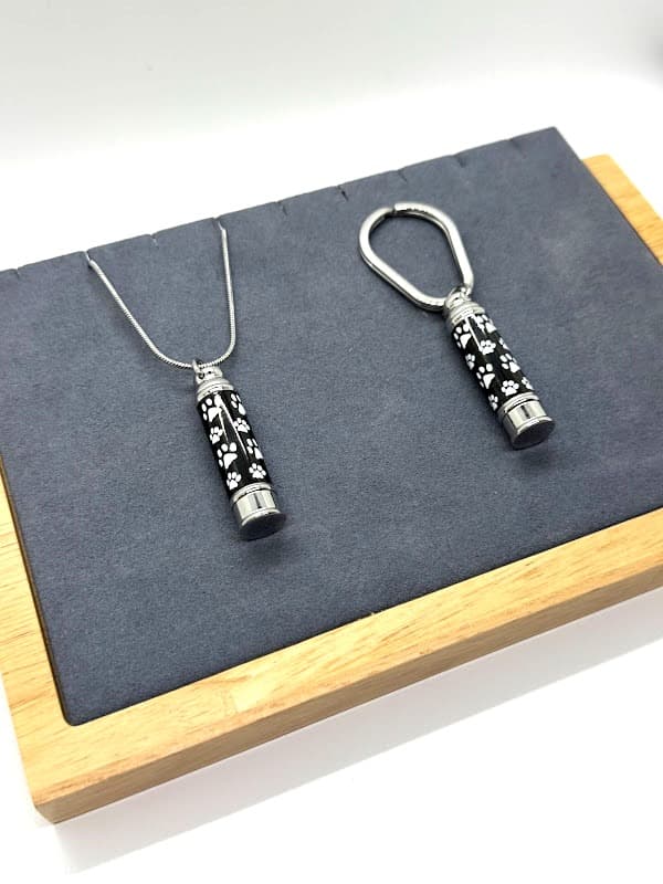 Cylinder keychain/pendant with black and white paw print design.