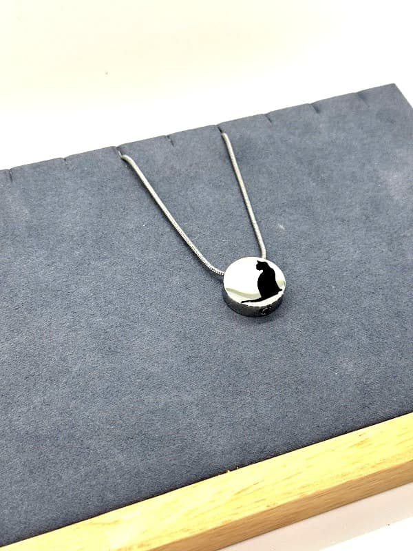 Silver pendant with cat silhouette design.
