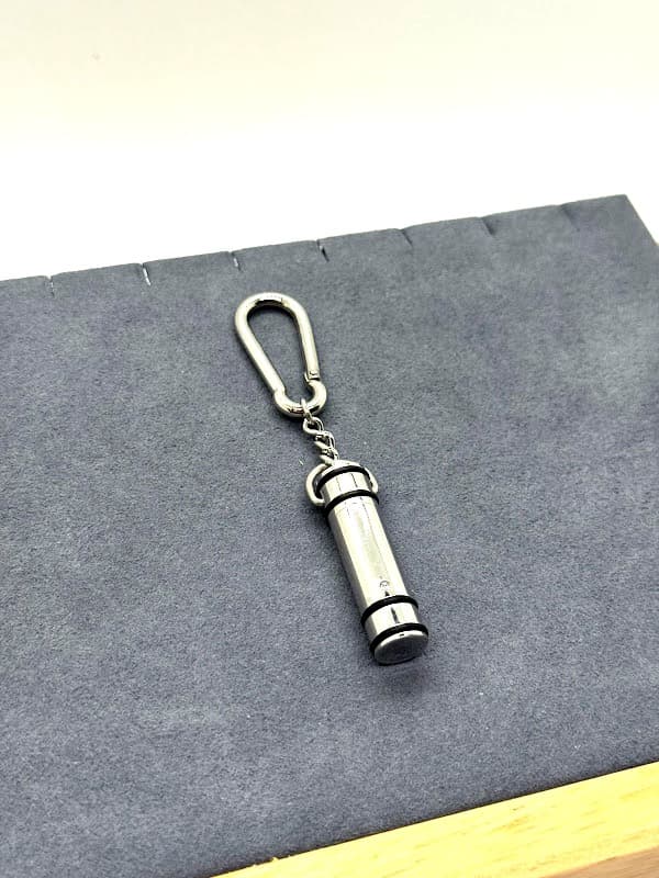 Silver cylinder keychain with clear crystal accent.
