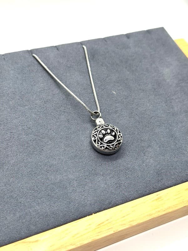 Silver necklace with encircled pawprint design.