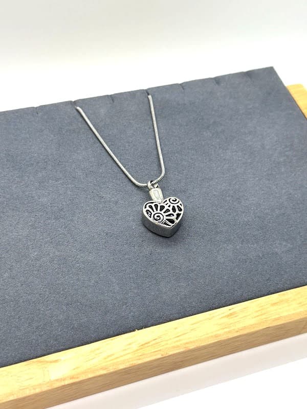 Silver heart pendant with floral design.
