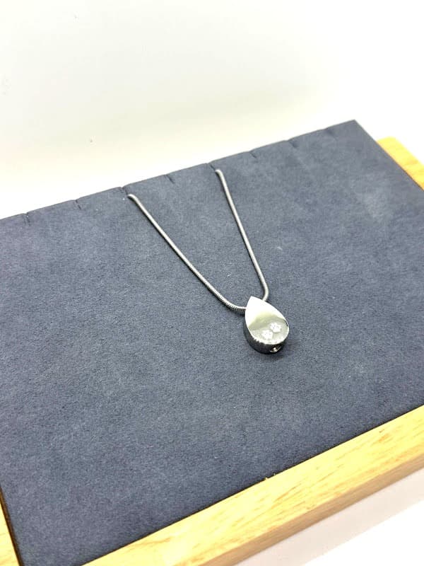 Silver teardrop pendant with paw print design.