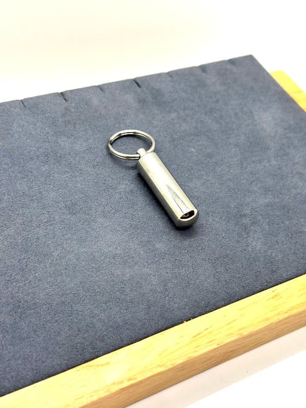 Silver sleek cylinder keychain with rounded bottom.