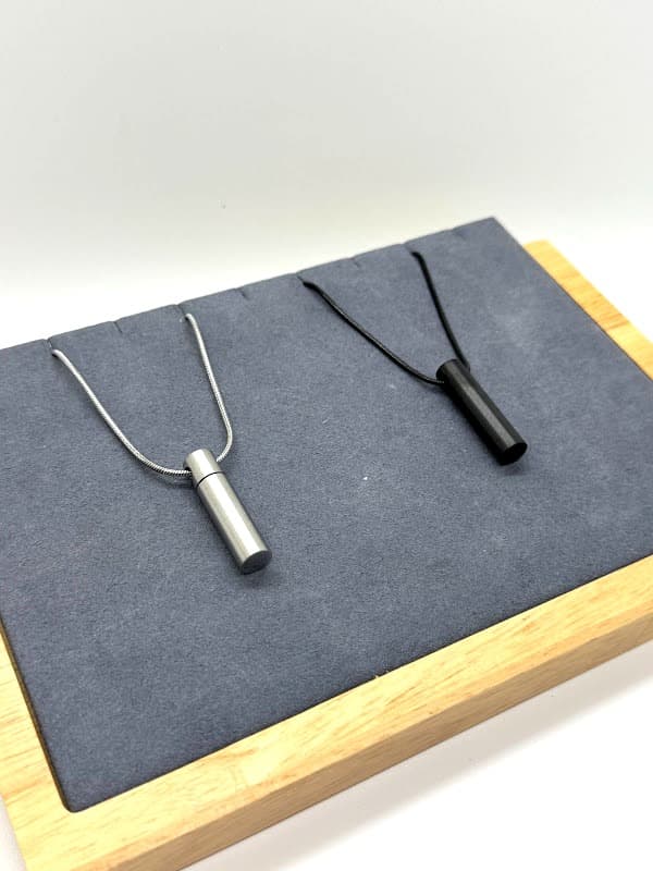 Sleek cylinder pendant. Available in silver and black.