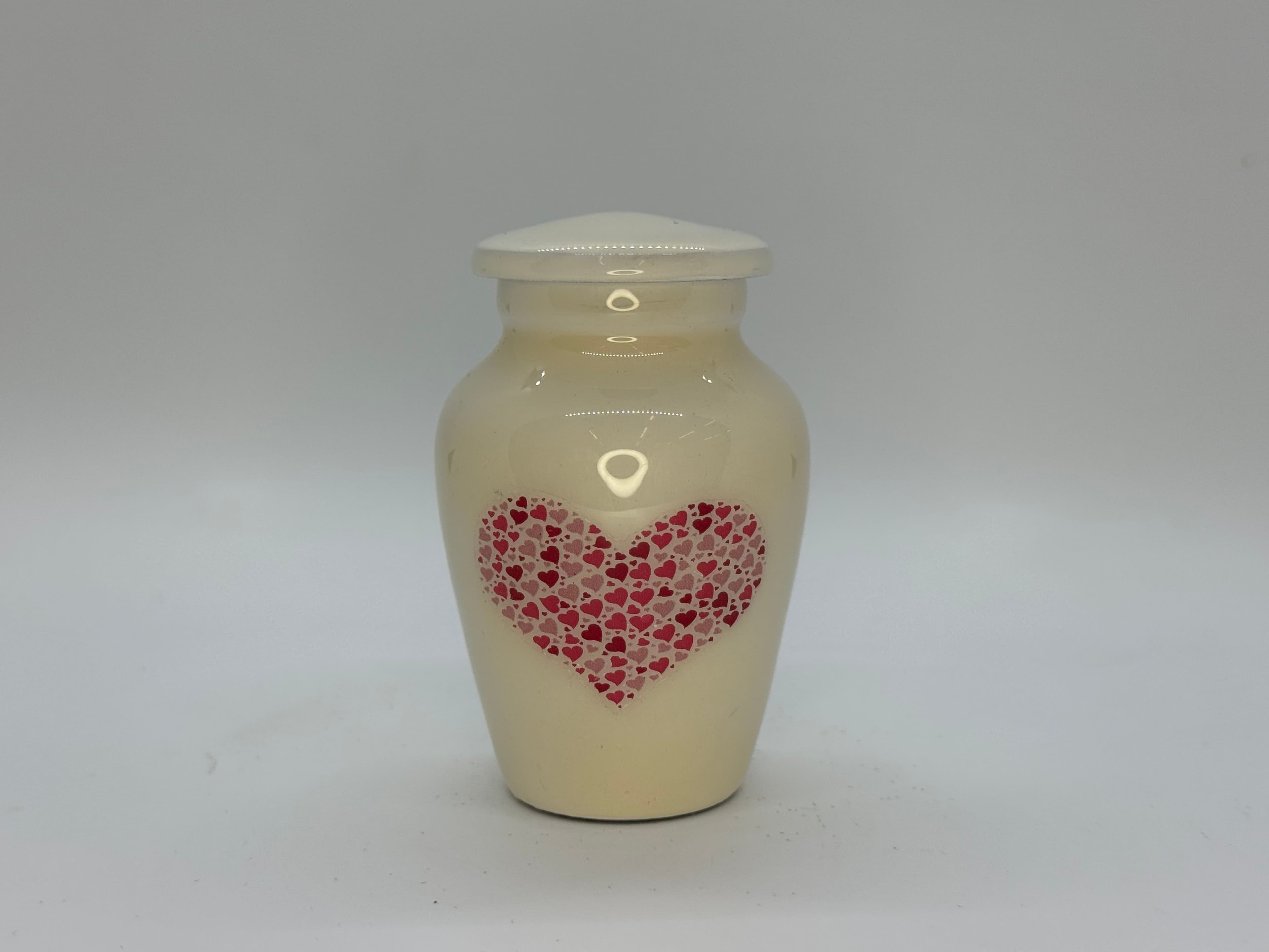 Cream colored metal alloy keepsake urn with pink heart detailing.
