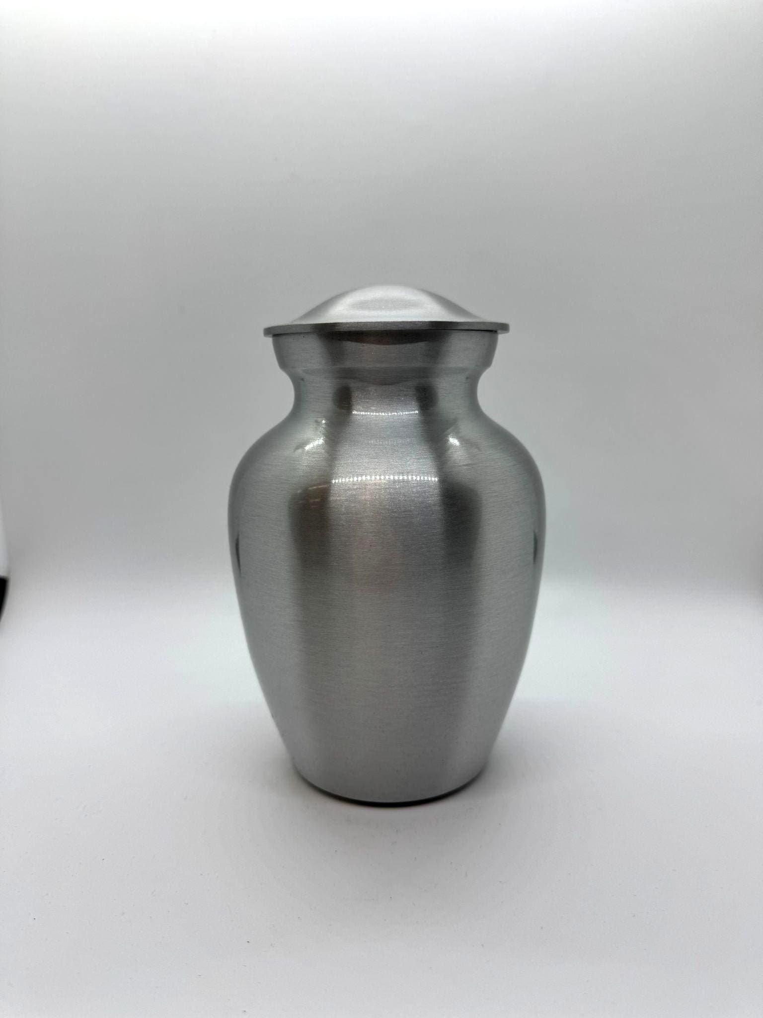 Brushed silver metal urn. S & M sizes are engraveable; L & XL are not.