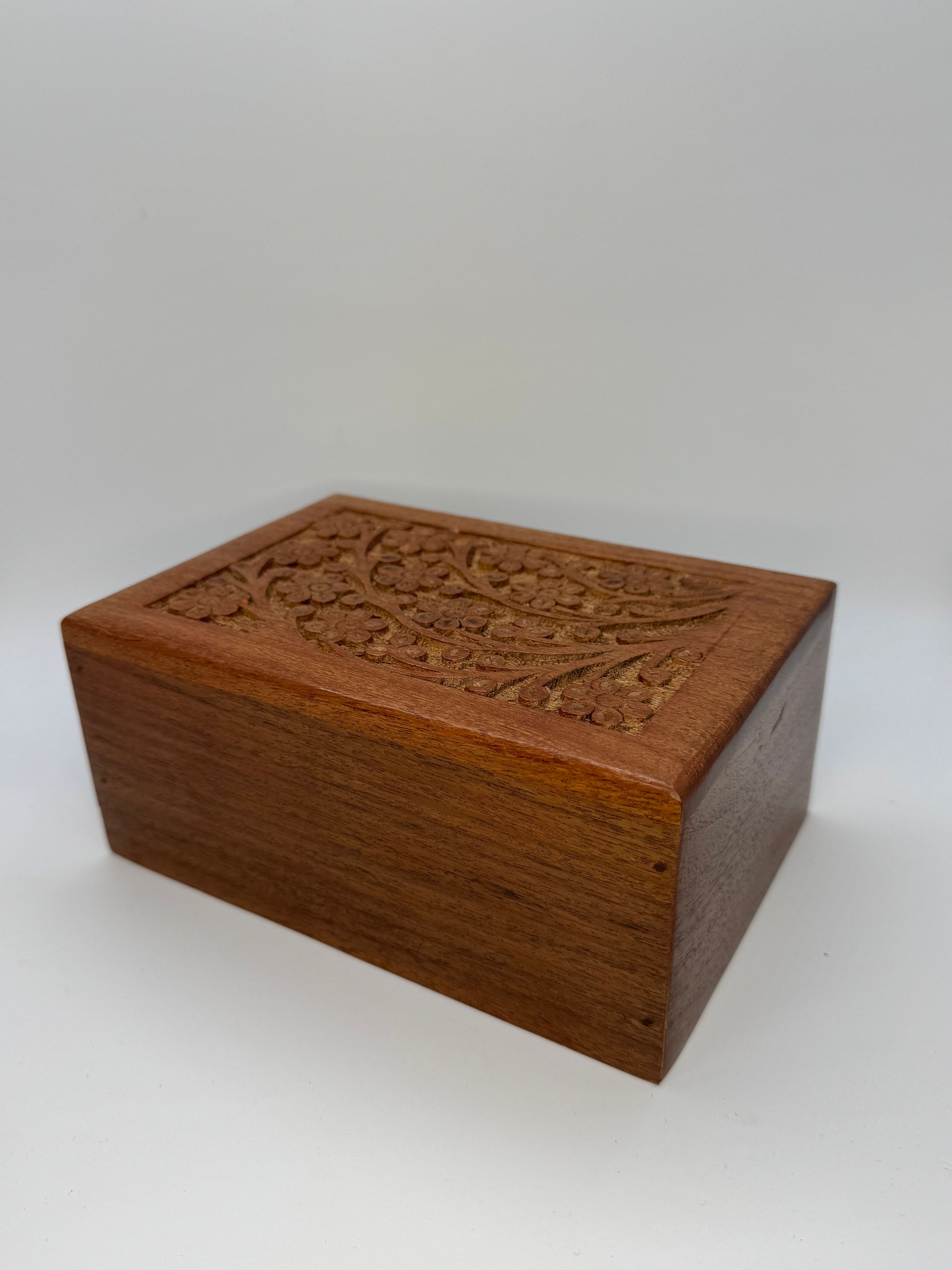 A Tree of Life carved into warm wood — one of our classic urns, chosen by many families.